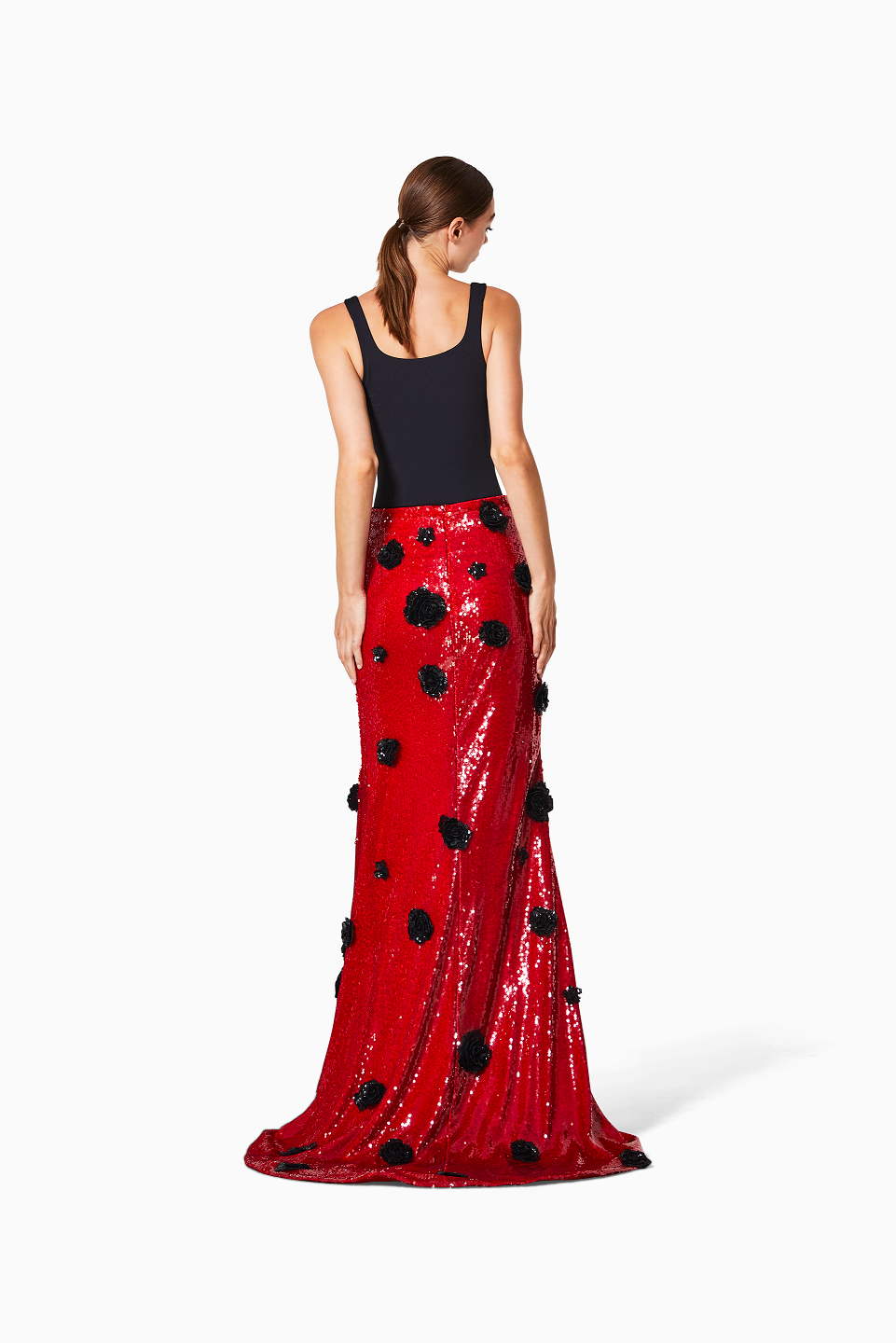 Woman wearing a red sequin skirt with black floral embellishments on a white background
