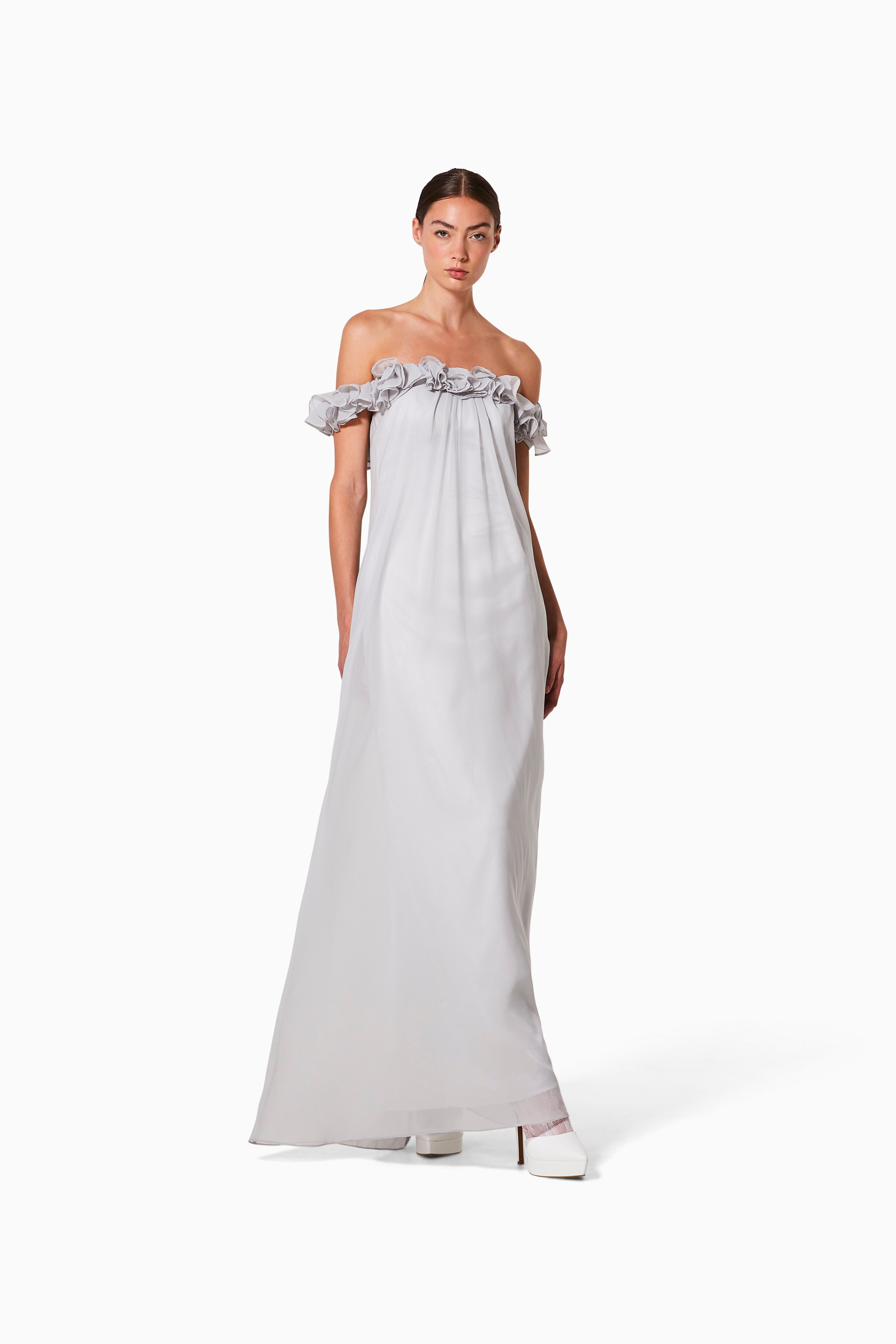 A model wearing a grey, cocktail gown with chiffon underlay and cotton stretch lining, featuring a ruffled, off-shoulder neckline and a flared skirt.