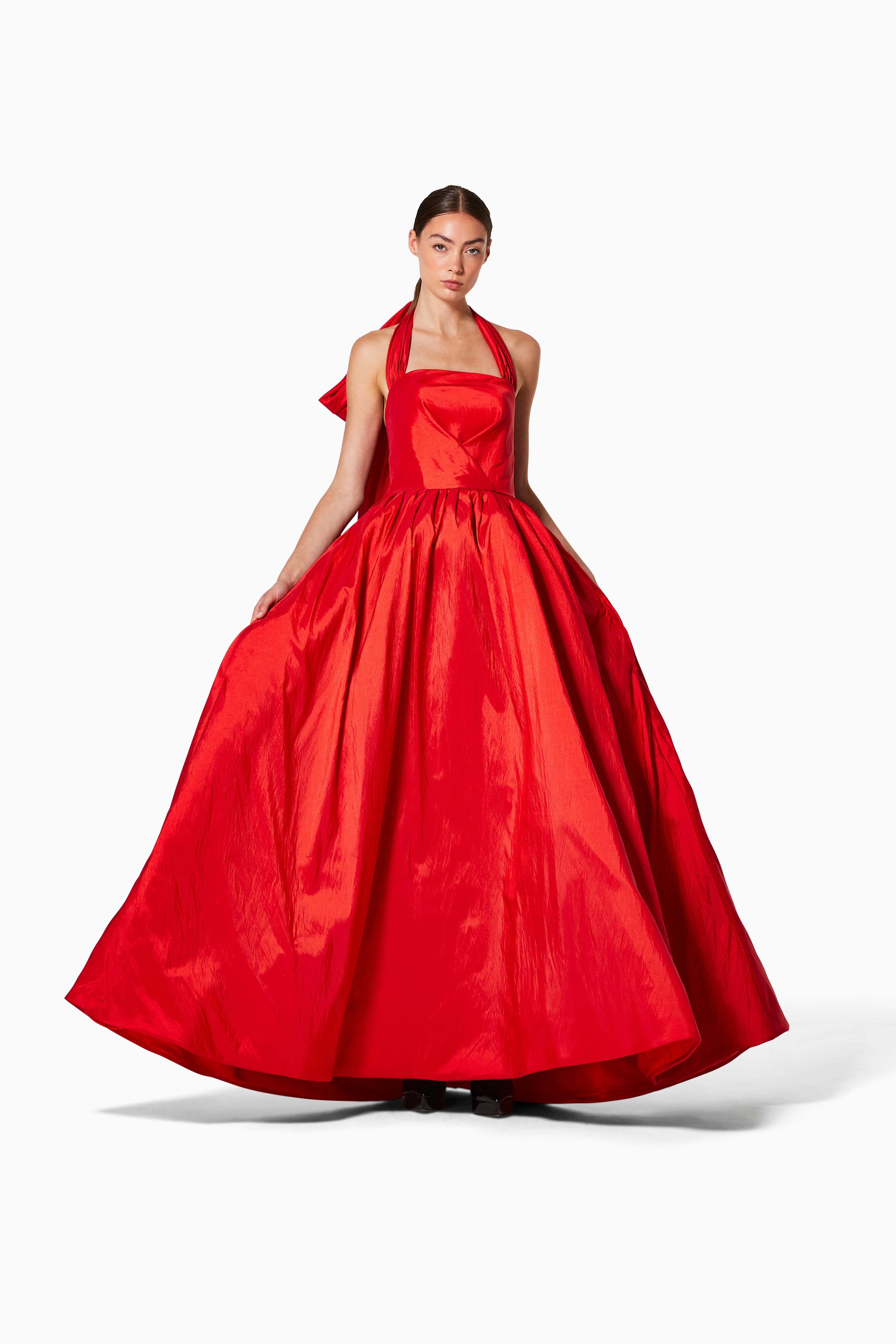A woman wearing a red, silk taffeta gown with a bow detail at the neck.