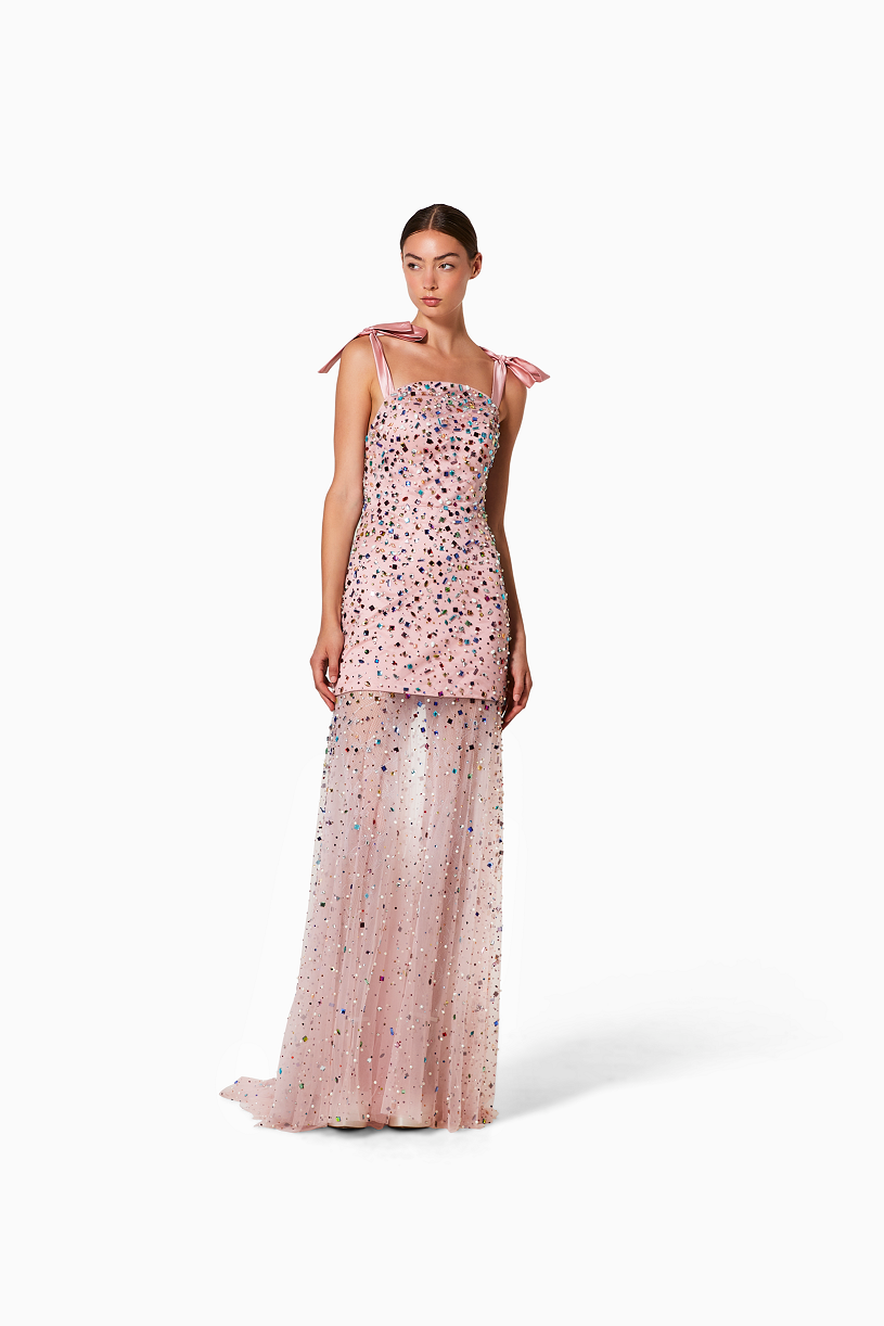 Woman wearing a pink evening gown with rhinestones on a white background