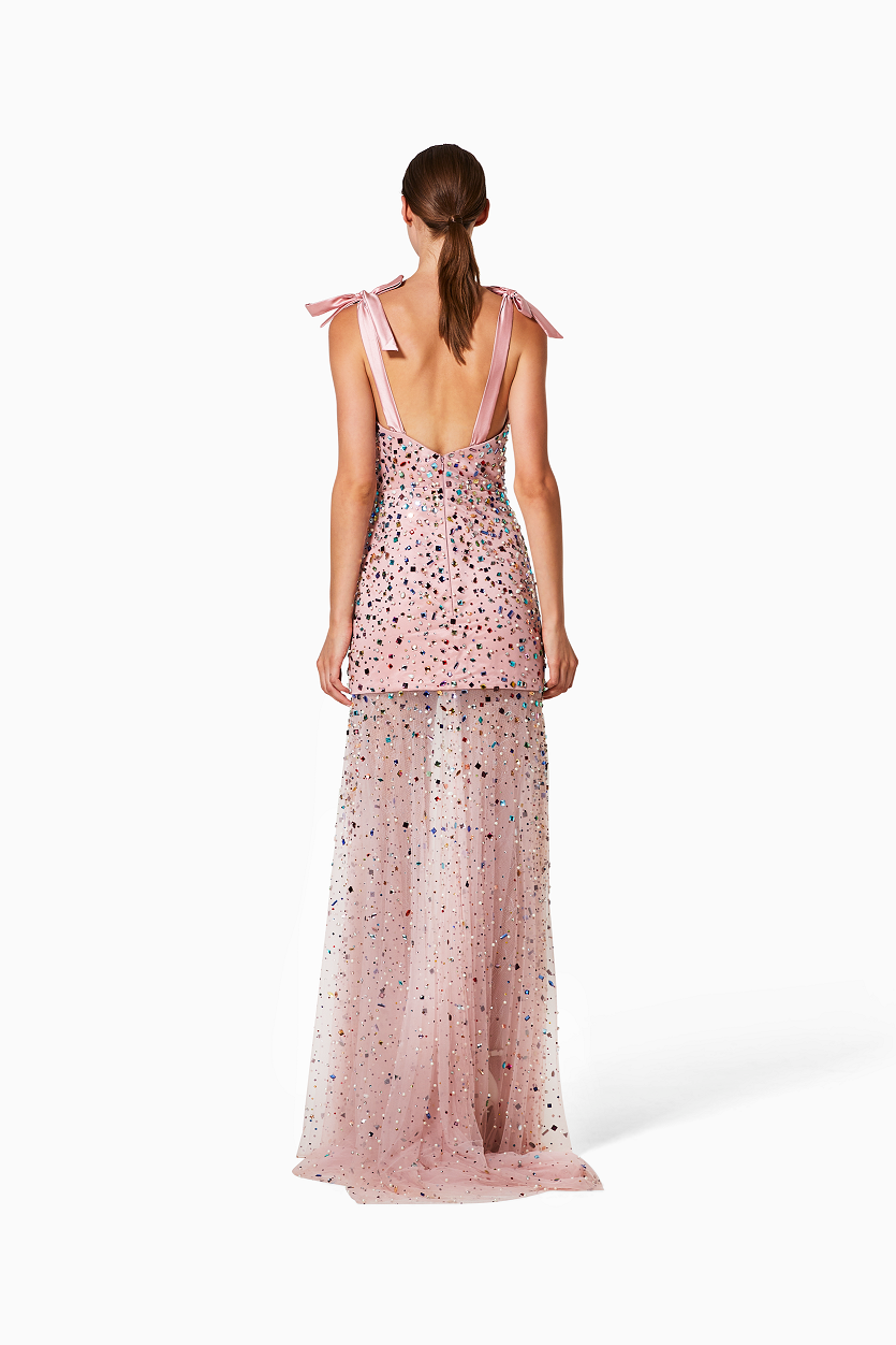 Woman wearing a pink floral dress with a sheer overlay on a white background