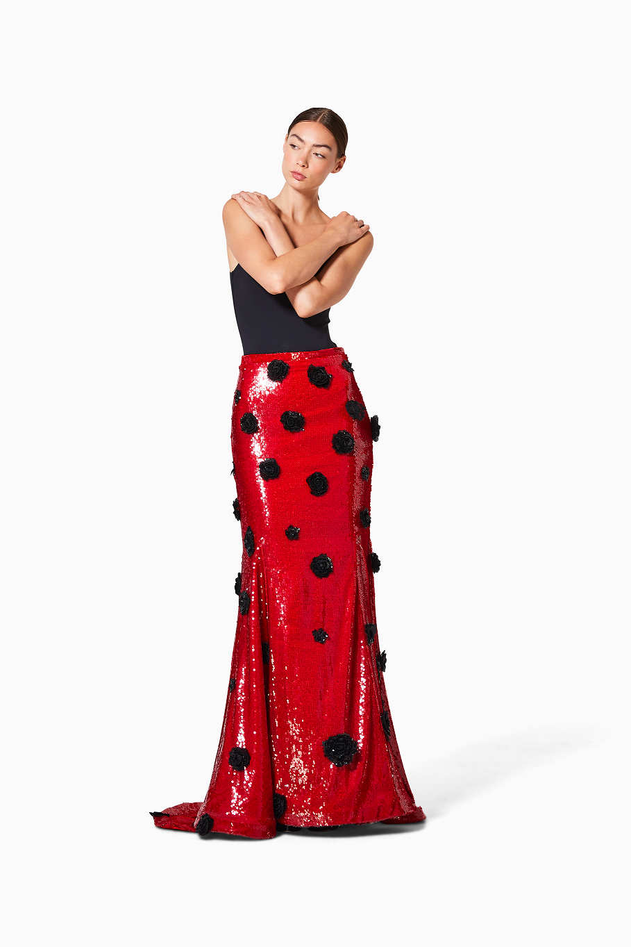 Woman wearing a red sequin skirt with black rosettes on a white background