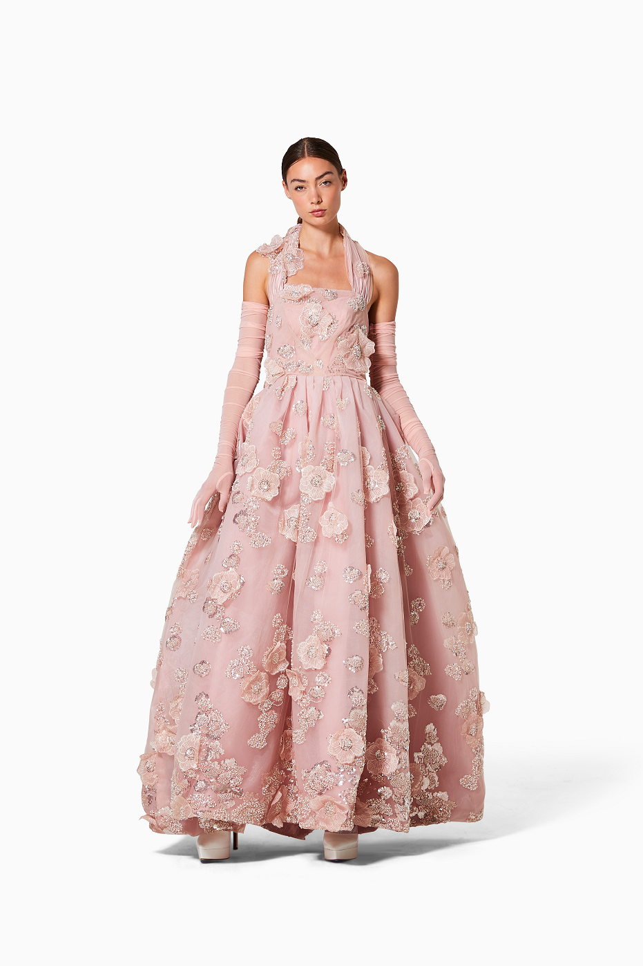 Woman wearing a pink floral dress with long gloves on a white background