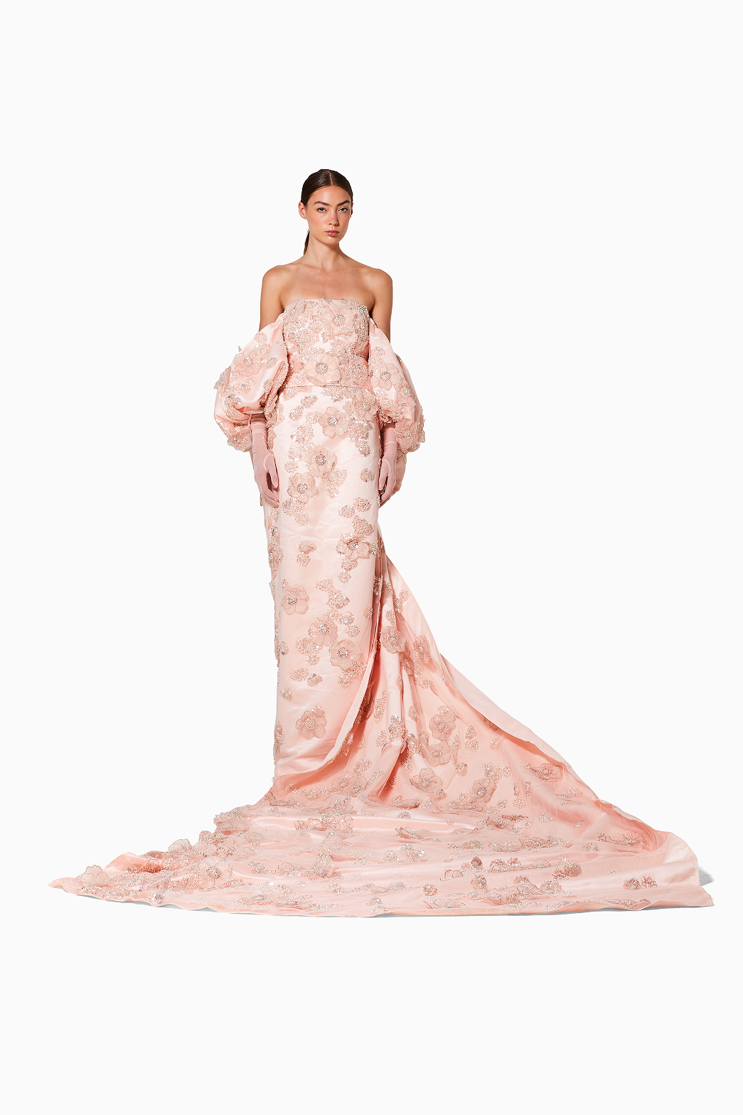 Woman wearing a pink strapless gown with floral details on a white background